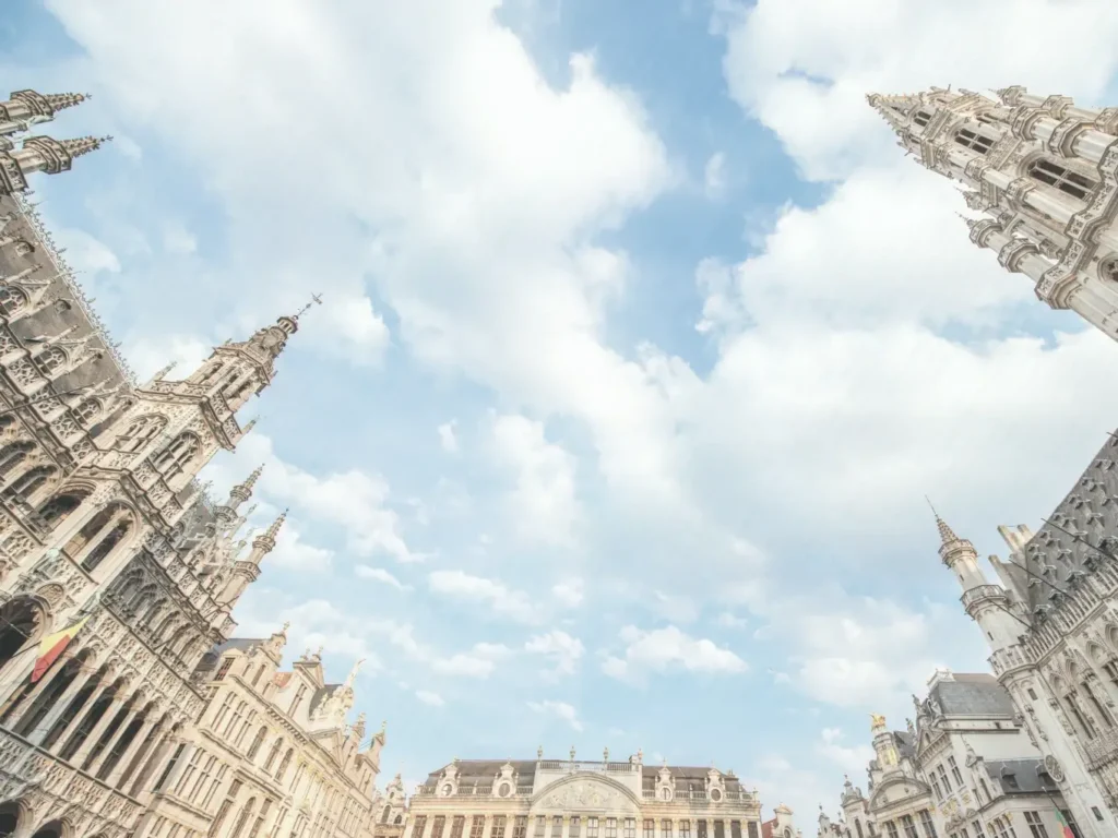 Historic stone city buildings viewed from below against a cloudy sky