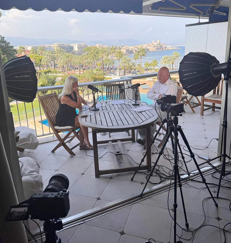 Kelly Palmer recording an interview on a terrace overlooking the bay in Antibes during Platform Global 2026